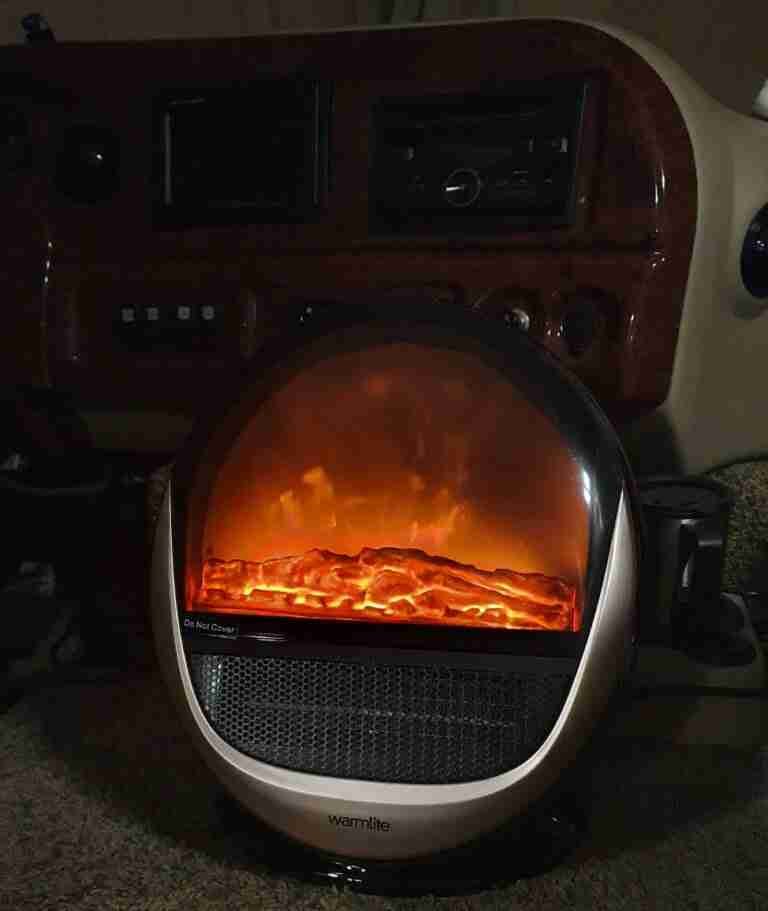 A portable electric heater with a glowing, fiery display placed in front of a vehicle's interior, providing a cozy atmosphere and warmth. small ceramic heater