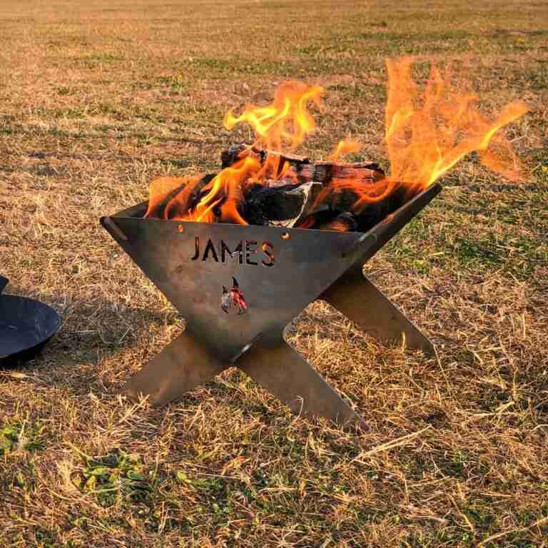 Personalized portable fire pits with the name "james" cut into the metal, aflame with bright, dancing flames against a dusky outdoor backdrop.
